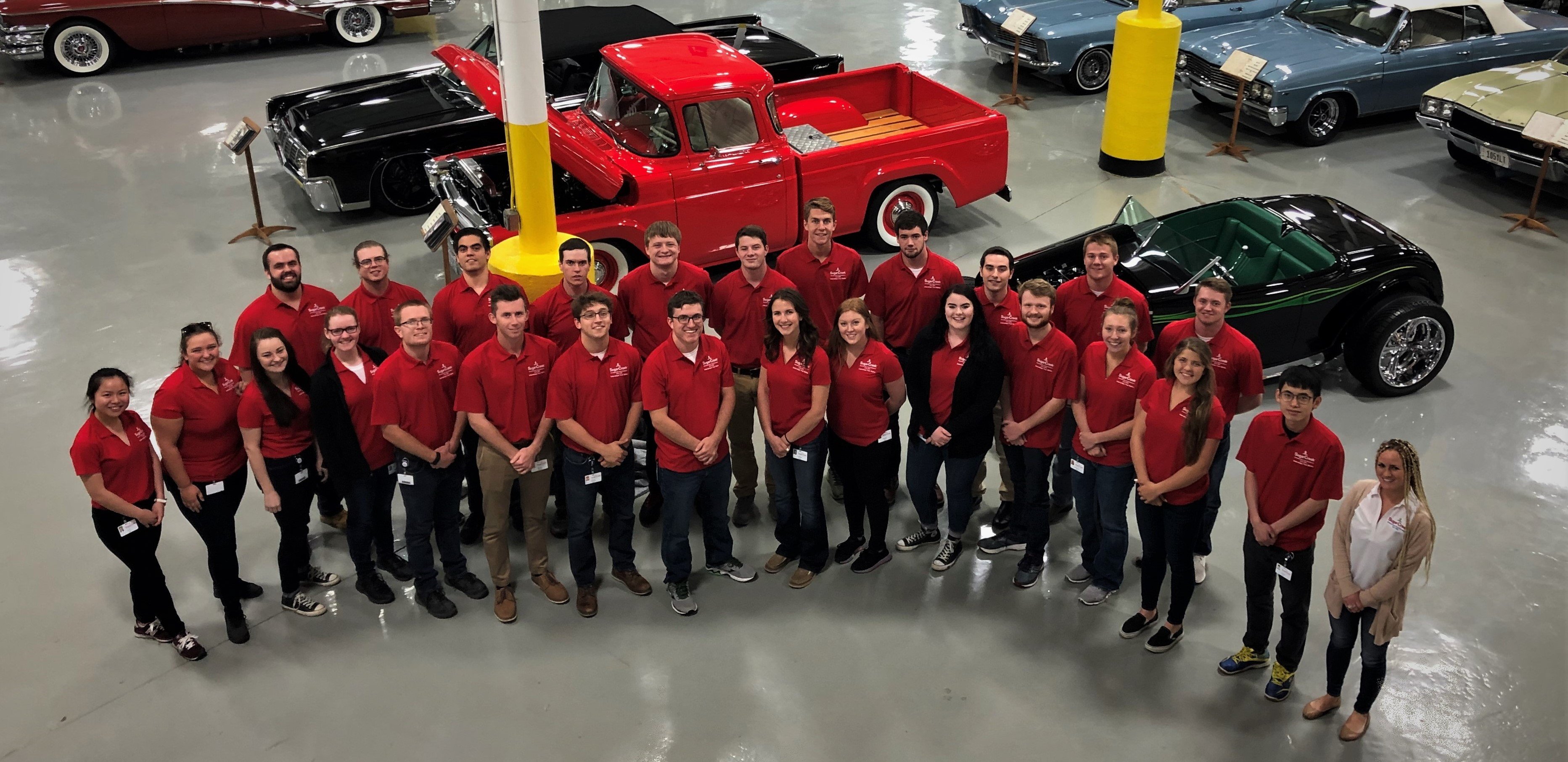 Group of Interns wearing red in an old fashion car garage