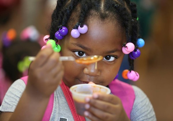 Young girl looking at spoon of food